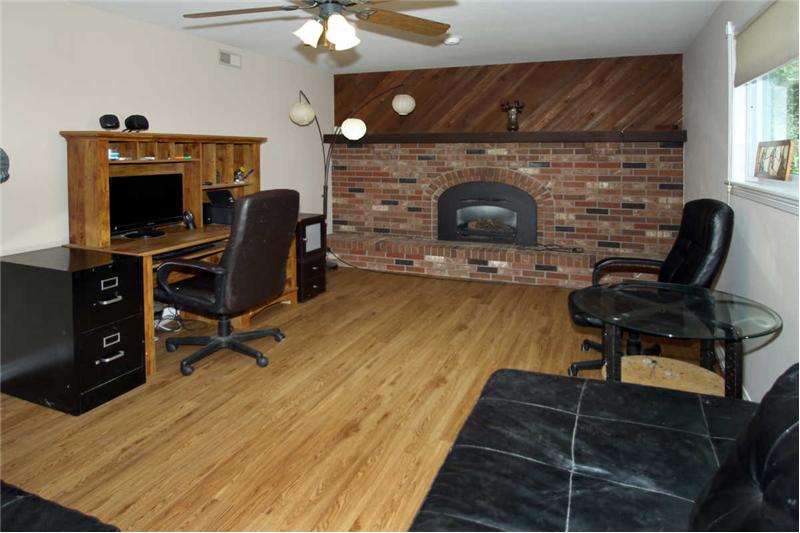 Bright family room in lower level has a gas fireplace, new wood laminate flooring, and walks out to large patio in backyard.