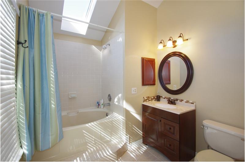 Master bath with large soaking tub, skylight, new vanity, and tile flooring