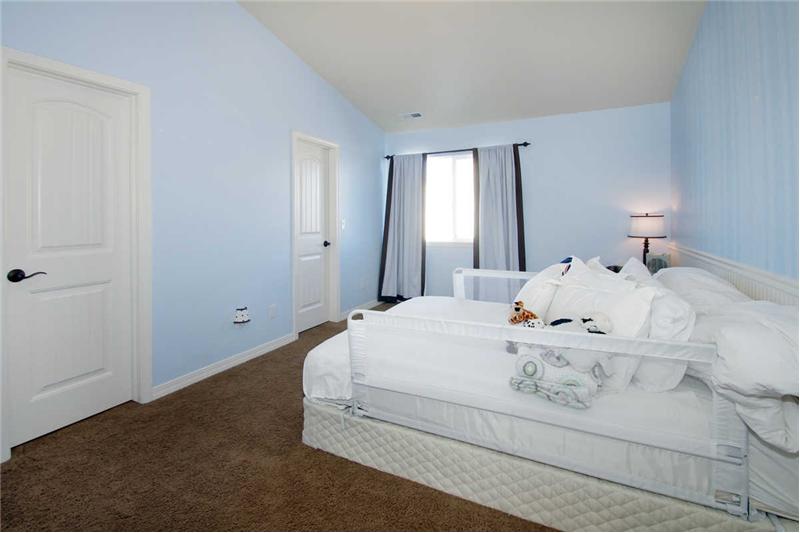 Secondary bedroom with walk-in closet and wainscoting. Vaulted ceilings throughout upper level!