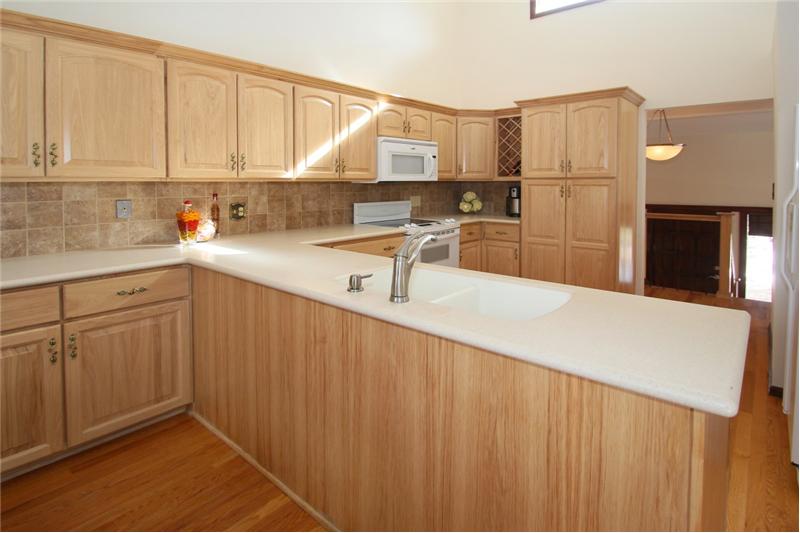 Hickory cabinets with under mount lighting, tile backsplash, and Corian counters