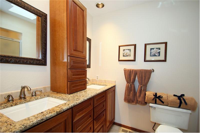 3/4 master bath with granite countertops, double sinks, and a skylight