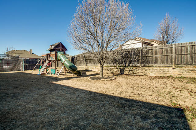 The backyard is spacious and surrounded by a wood fence.