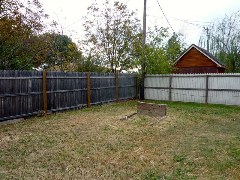 The large backyard is surrounded by a wood fence.