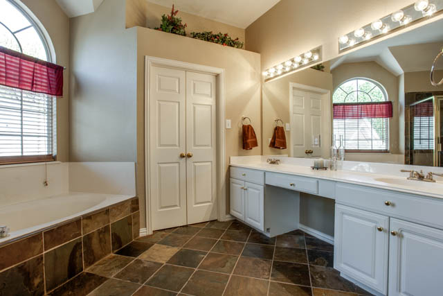 Master bath features slate flooring, dual vanities, and a huge shower.