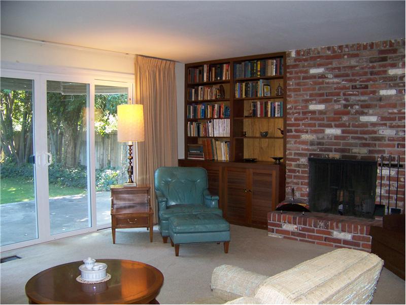 Lovely living room with brick fireplace and hearth surrounded by built in bookcases